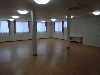 フローリングのフロアの共有スペースには家具や家電は置かれておらず、大きな窓がたくさんあり、カーテンが付いている。