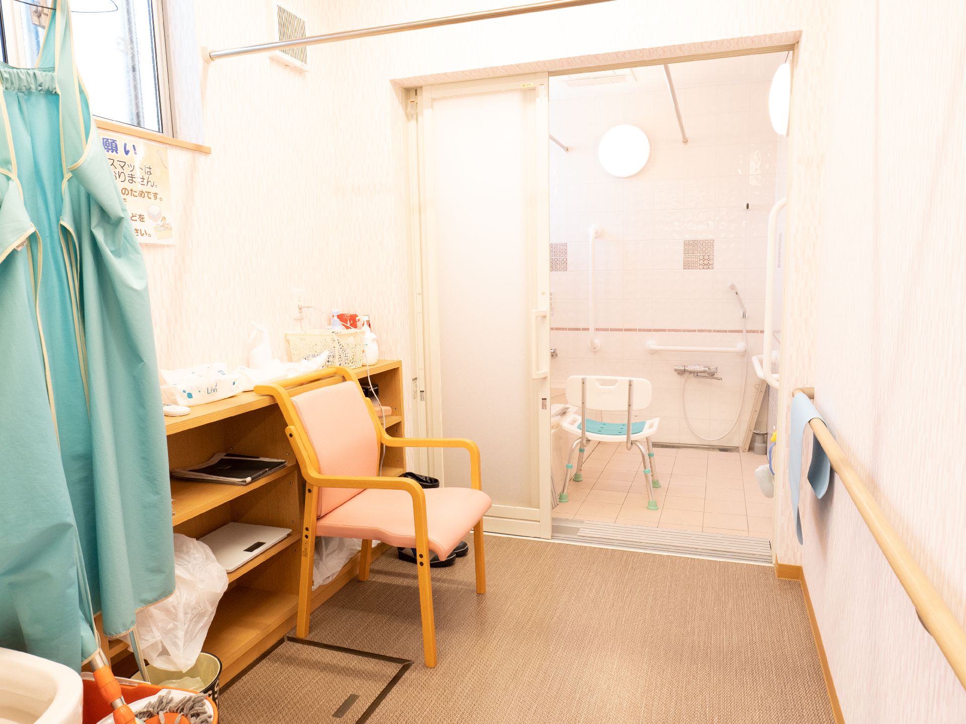 エプロンを付けた若い男女のスタッフが車いすの高齢女性と付き添いの高齢男性を囲んで笑っている。