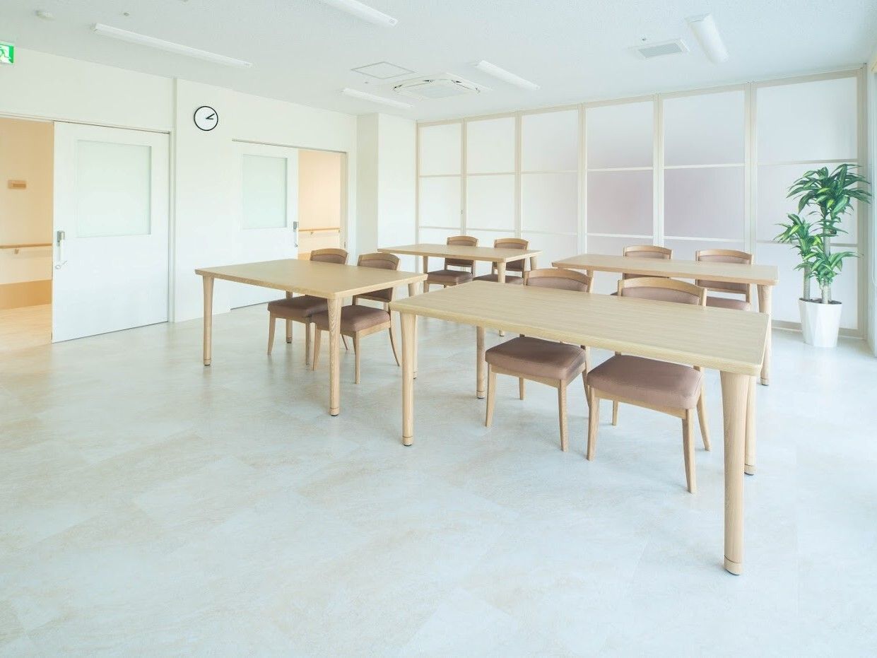 ２階建ての建物はブラウン系で屋外階段が付き、目の前には運動場が広がっている。周りには建物はない。