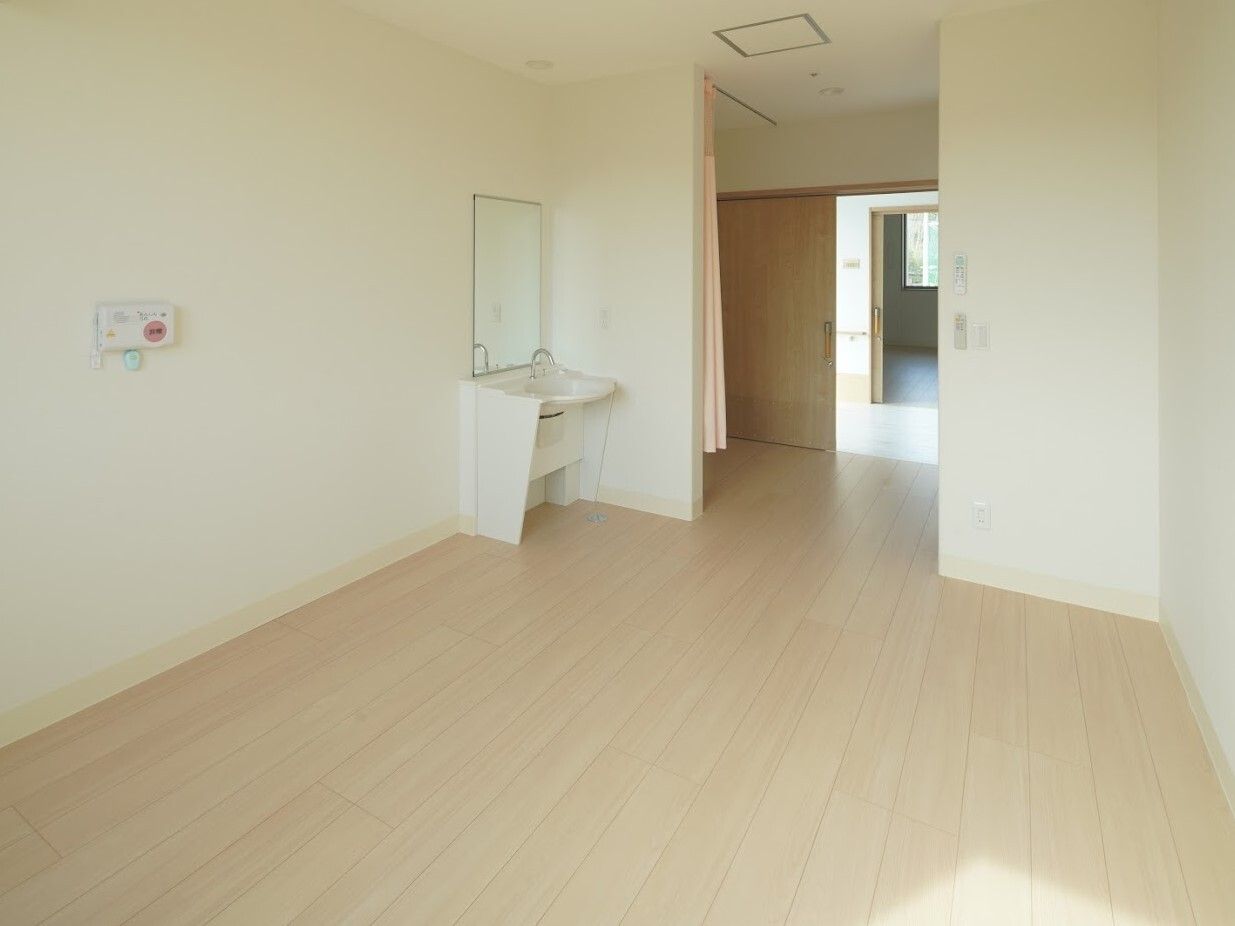 洗面台がついた施設内のワンルームの居室。壁に緊急コールが取り付けられている様子