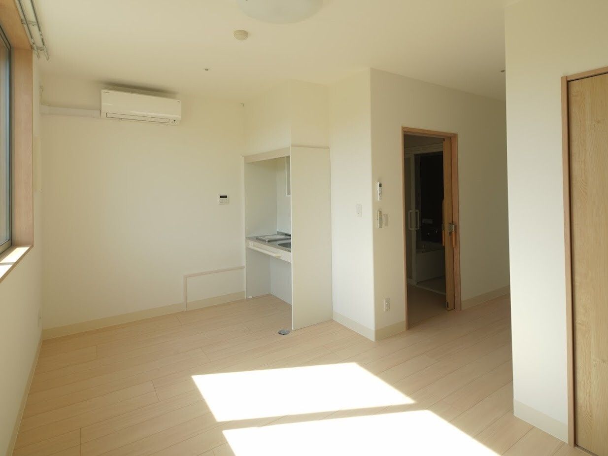 小さなキッチンがついた一人用のワンルームの部屋。施設内の居室の写真