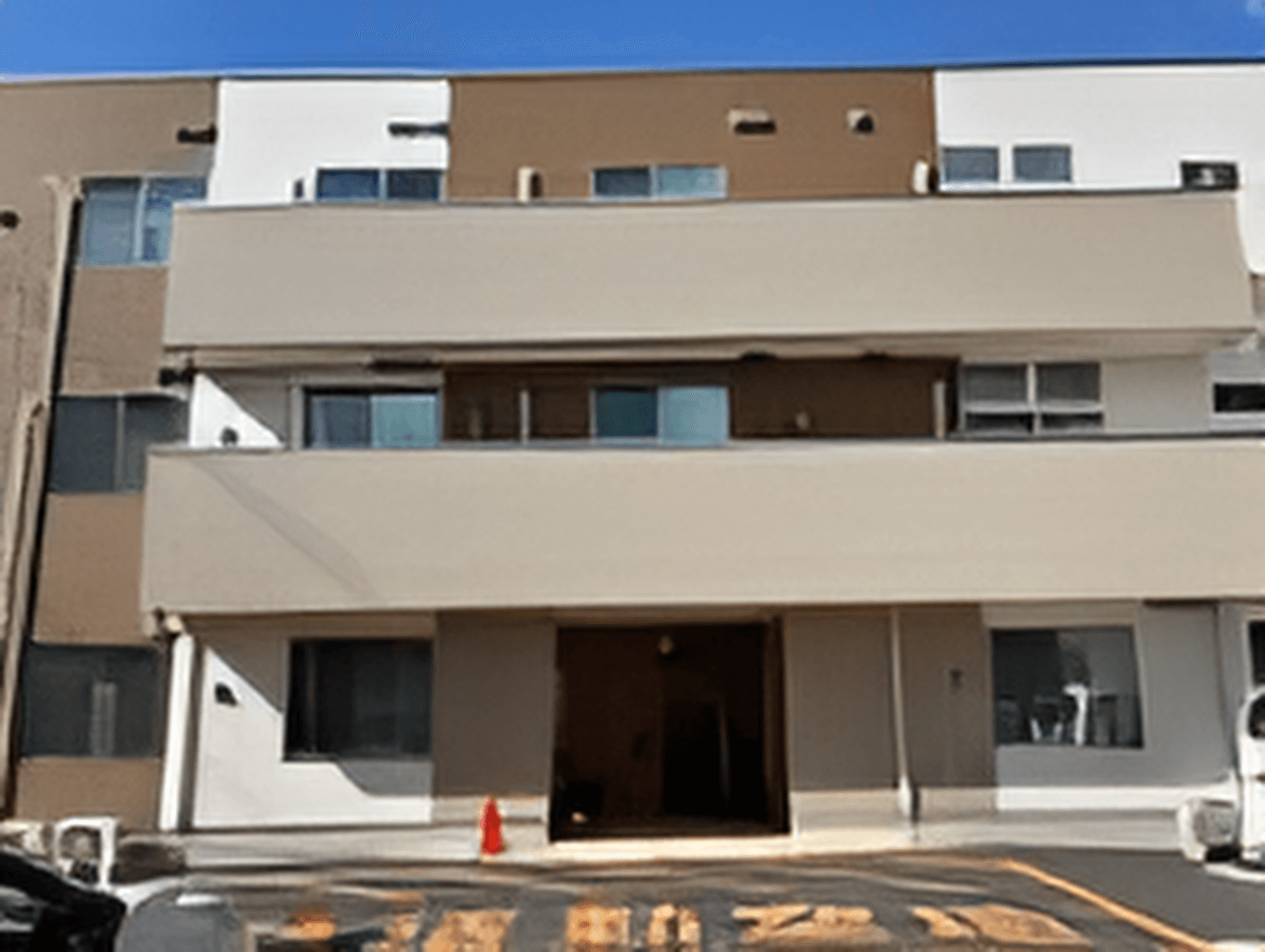 カルテのようなものを見ながら真剣な表情で話しているピンクのエプロンを付けた女性スタッフと高齢女性。