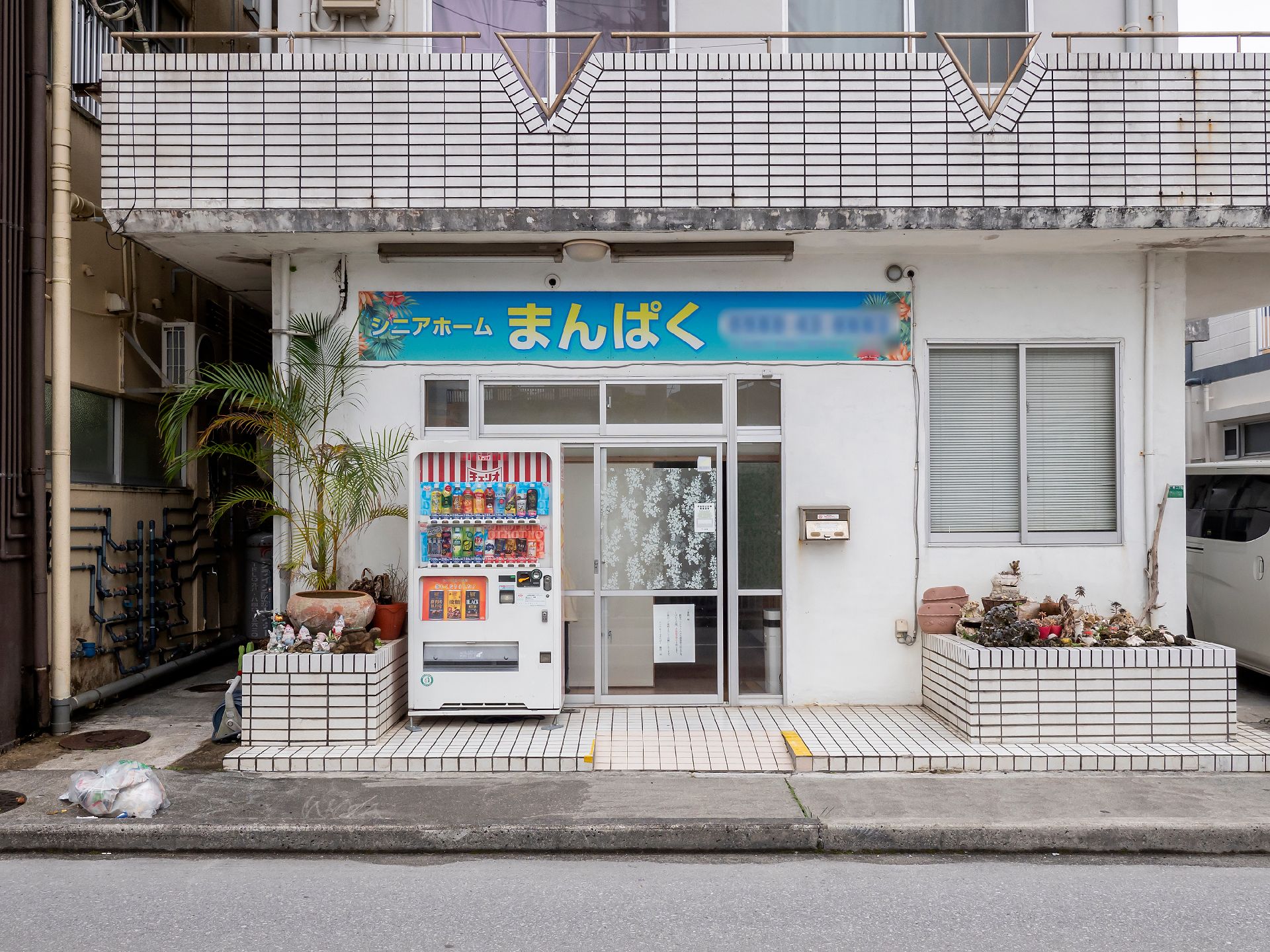 ブルーのユニフォームを着た男性スタッフと高齢女性が並んで立ち、笑顔で体操をしている。