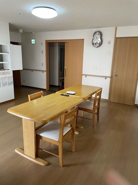 ブルーのユニフォームを着た男性スタッフと高齢女性が隣同士に座り、赤いロープを使ったエクササイズをしている。