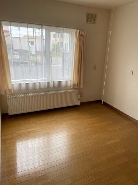 原っぱのような場所を歩いているブルーのエプロンを付けた若い女性スタッフとブラウンのジャケットを着た高齢女性。