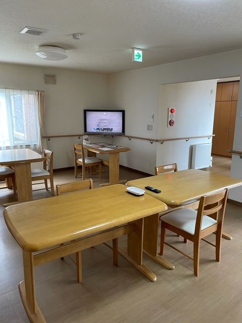 丸みを帯びた少人数用のダイニングテーブルが複数置かれている食堂。壁には手すりが付き、テレビも設置されている。