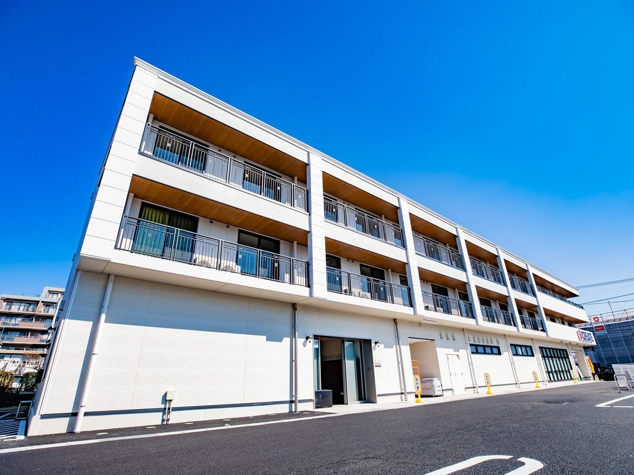 3階建ての建物は白系で各フロアにベランダがあり、１階の一番奥にはドラッグストアが入っている。