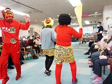 赤いつなぎを着ていたり、トラのパンツをはいていたりと、赤鬼に仮装した３名のスタッフに拍手をするスタッフたち。