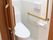 エル字型の手すりが付いたトイレ内にはオレンジの呼び出しボタンもあり、ドアはスライド式。
