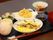 ちらし寿司や天ぷら、茶碗蒸し、野菜の小鉢などが並べられた黒いトレー。赤い箸が添えられている。