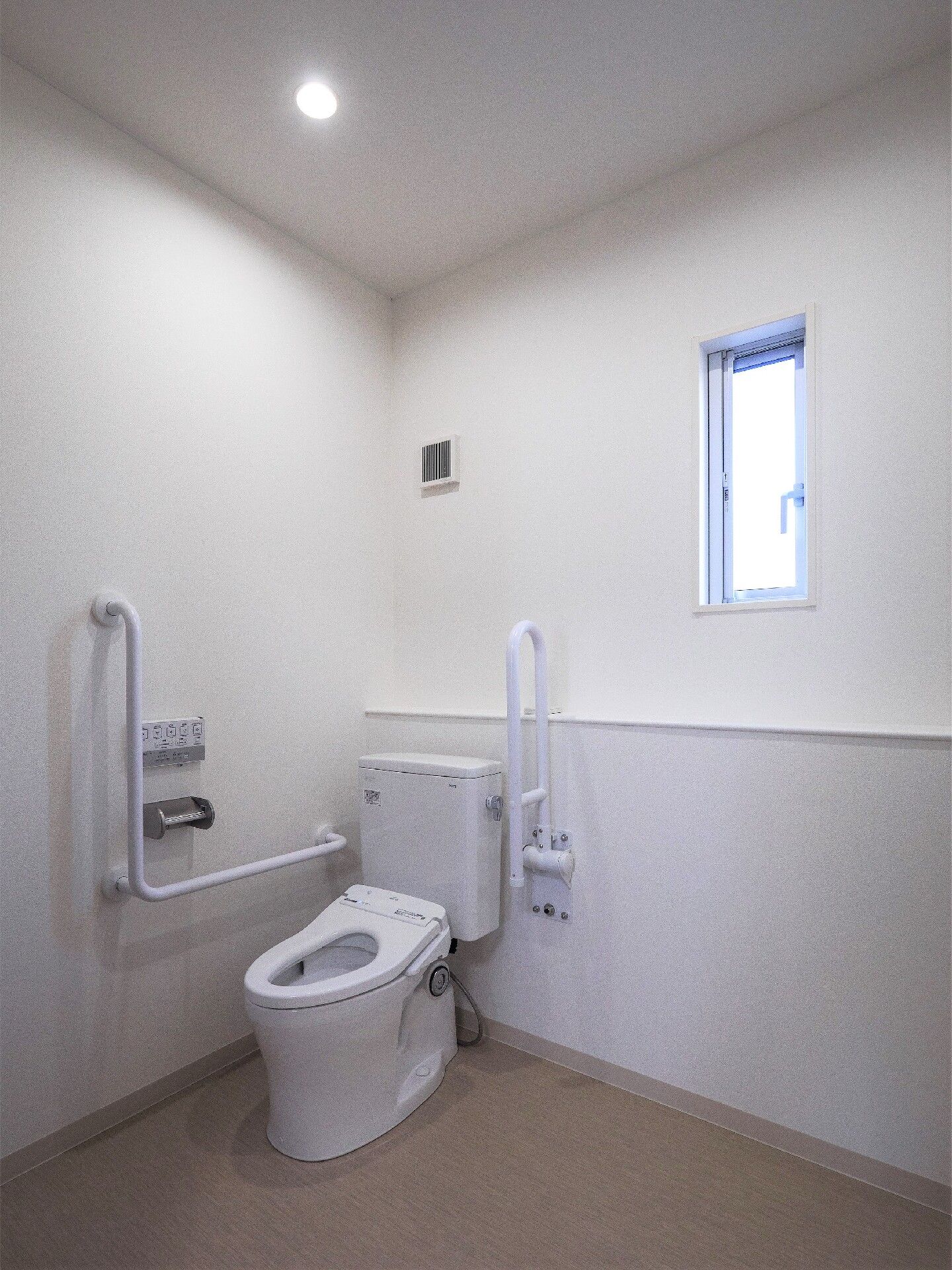 エル字型と可動式の手すりがついた施設内の車いす用トイレの様子