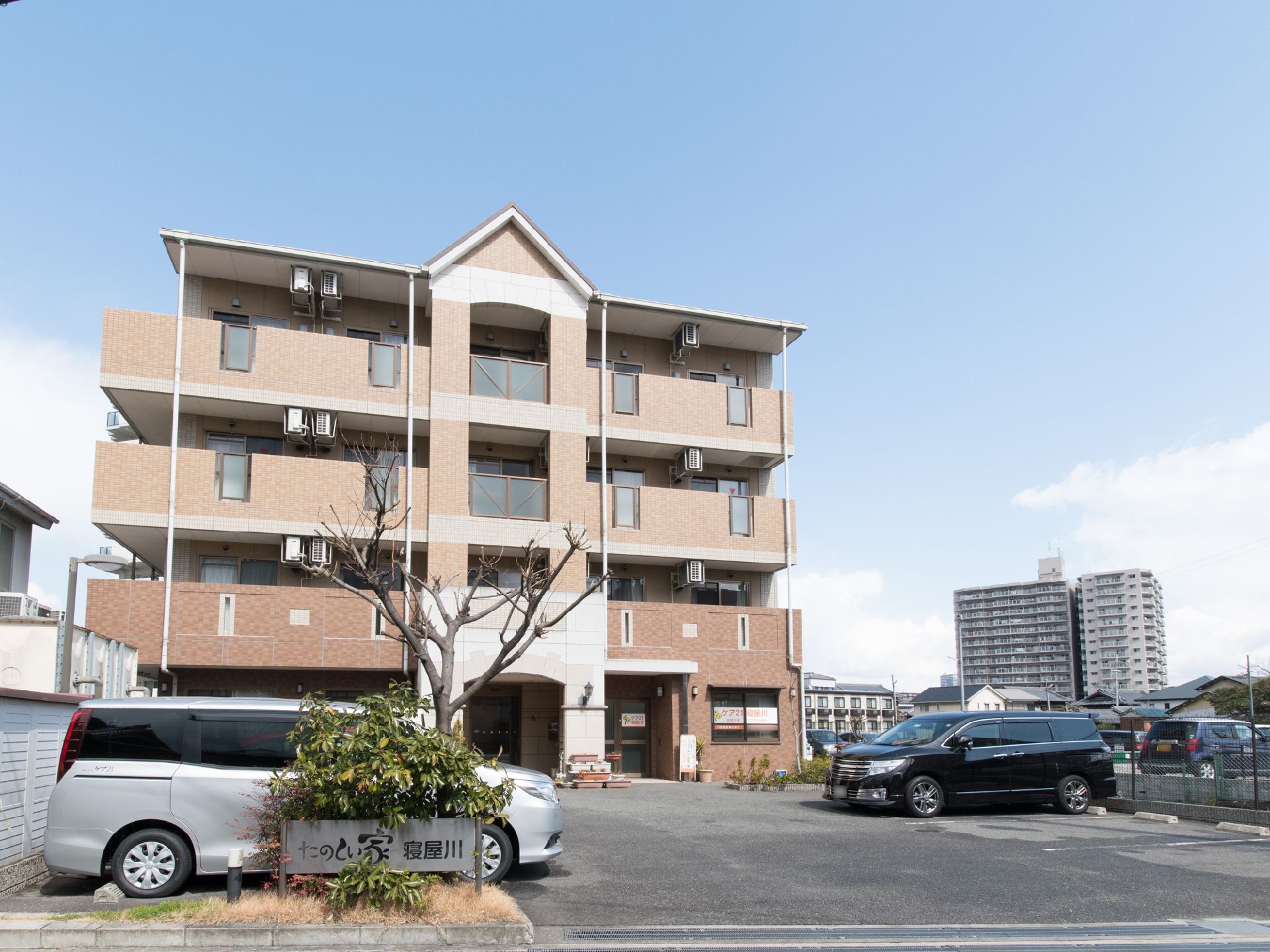 全室エアコン完備している。駐車場前に施設看板が設置されている。茶系の落ち着いたモダンなデザインである。