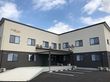 エル字型の建物は2階建てで2階部分がベージュ、下の階がダークブラウンでカラフルな文字で住宅名が書かれている。
