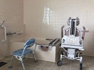 簡易機械浴が設置された浴室は洗い場が広く、シャワーチェアや手すりが付いている。