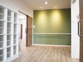 段差のない玄関には白い大きなオープンタイプの靴箱が置かれ、壁には手すりが付いている。