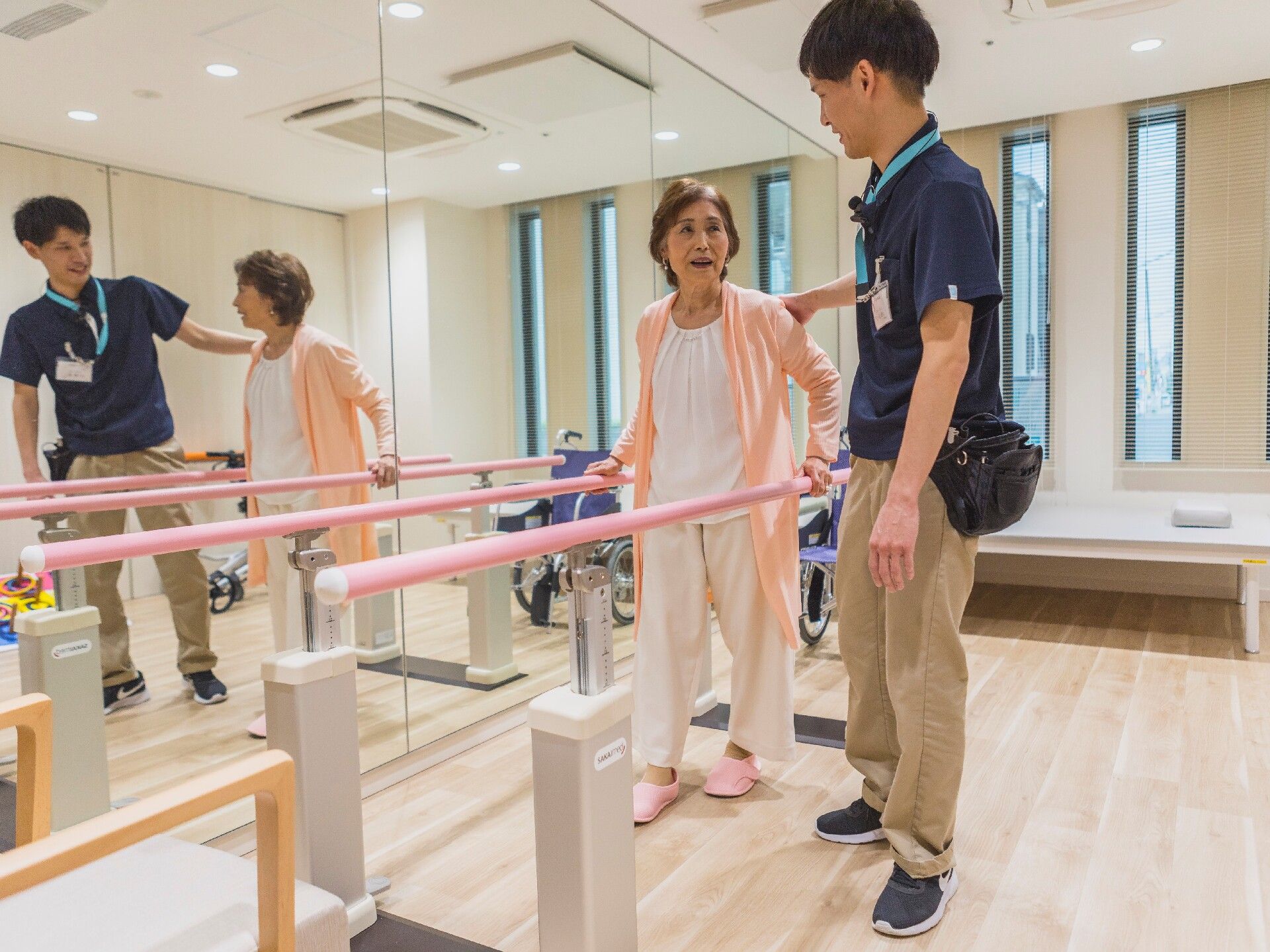 からだを動かしている高齢女性と男性スタッフの様子。施設内で体操しているときの一場面