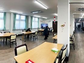 少人数用のダイニングテーブルが複数置かれた食堂には手作りの飾りが飾られている。右側にはまっすぐな廊下がある。