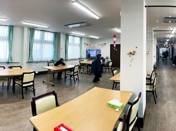 大きな窓がたくさんついた食堂には少人数用のダイニングテーブルが複数置かれ、右側にはまっすぐな廊下が続いている。