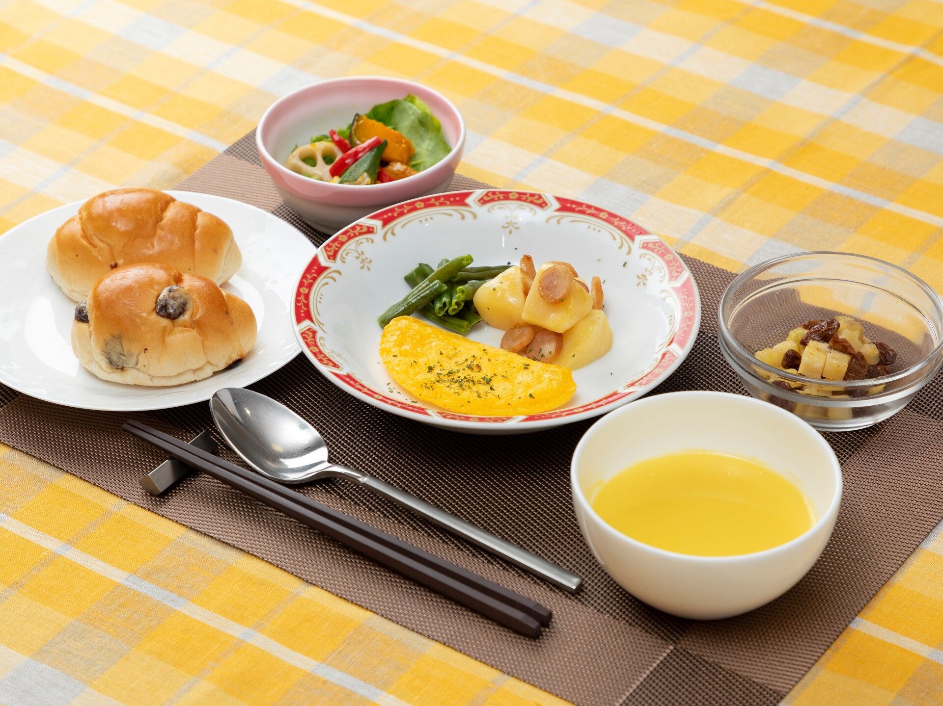 オムレツにはいんげんやジャーマンポテトが添えられ、かぼちゃのスープやレーズンパン、サラダなども並んでいる。