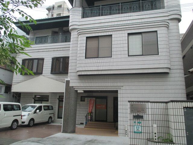 なにかを見て笑顔で手をたたいている高齢女性とスタッフの様子。施設での一場面の写真