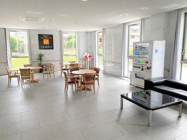 大きな窓の外には緑が広がっていて、館内にはテーブルセットやソファスペースがあり、自動販売機が置かれている。