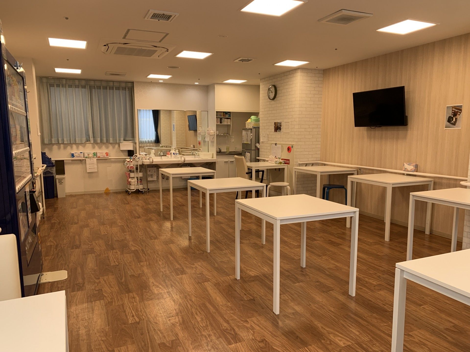 ボーダー柄のエプロンを付けた女性スタッフが笑顔で白いシャツを着た高齢男性の介助に当たっている様子。
