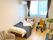 寝具付きのベッドが置かれたフローリングの部屋には車いすやソファ、エアコンなどもある。