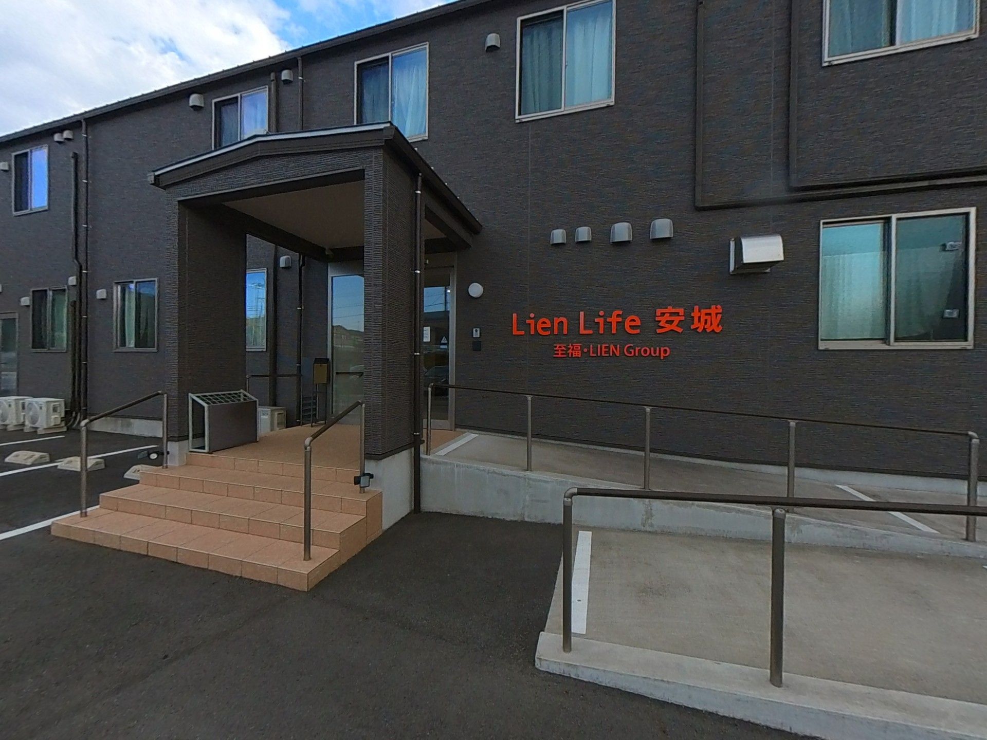 カメラに向かって笑顔を見せるスタッフと高齢者の女性。施設での何気ない一場面の様子