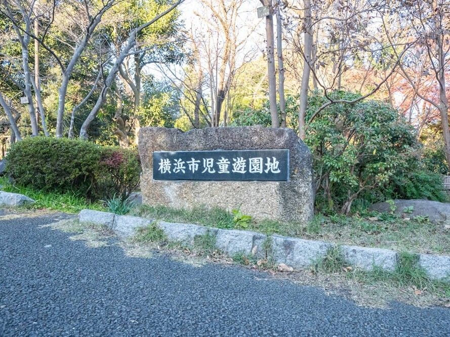 正面の大きな石には「横浜市児童遊園地」と白い文字で書かれた黒いプレートが貼られている。