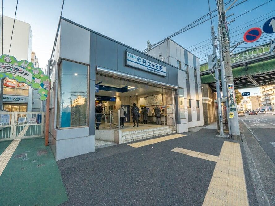 「井土ヶ谷駅」と書かれた建物内にはたくさんの人が行き来していて、右側には道路、左側にはキッズランドがある。