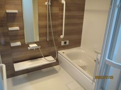 縦横に手すりが設置された家庭的な雰囲気の浴室。浴槽内にはベンチがあり、シャワーも付いている。