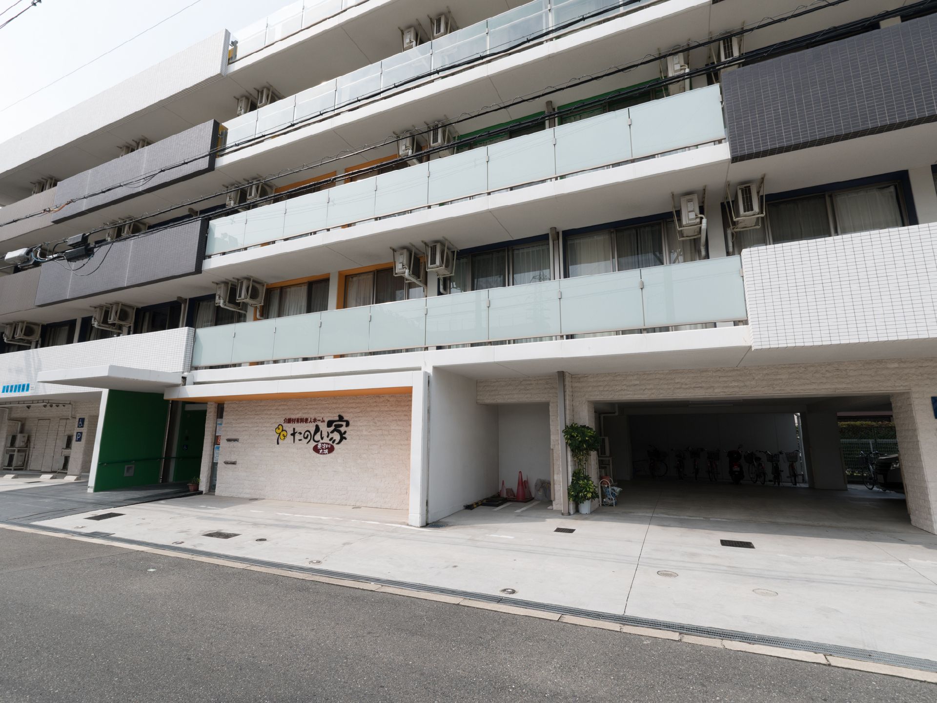 道路側から見た施設の外観の様子。白と黒のタイル外壁で、ベランダもある。マンションのような風貌。