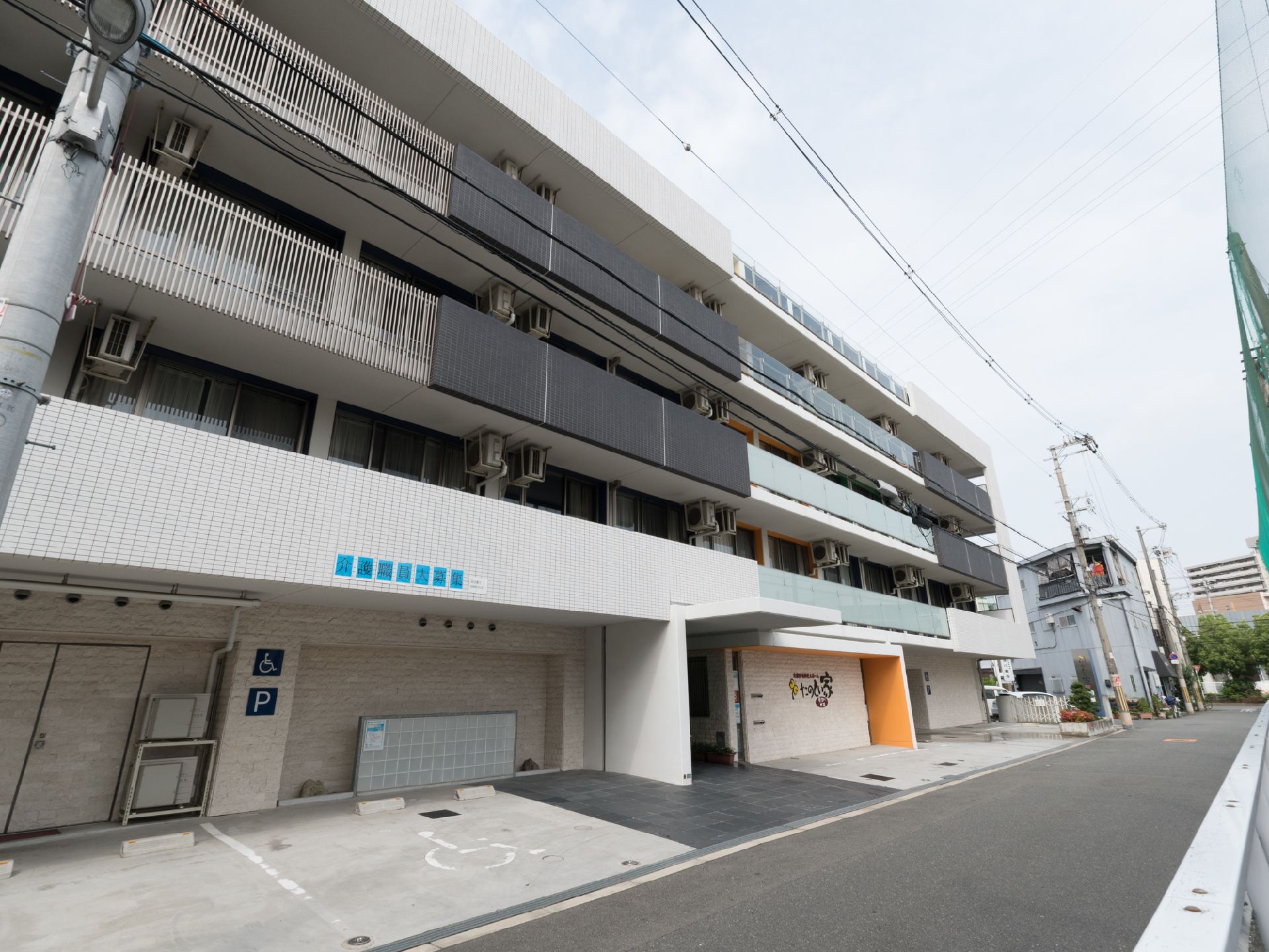 外観を写した画像。施設の前には、車椅子利用者でも使いやすいように、スペースを広く取った駐車場が用意されている。
