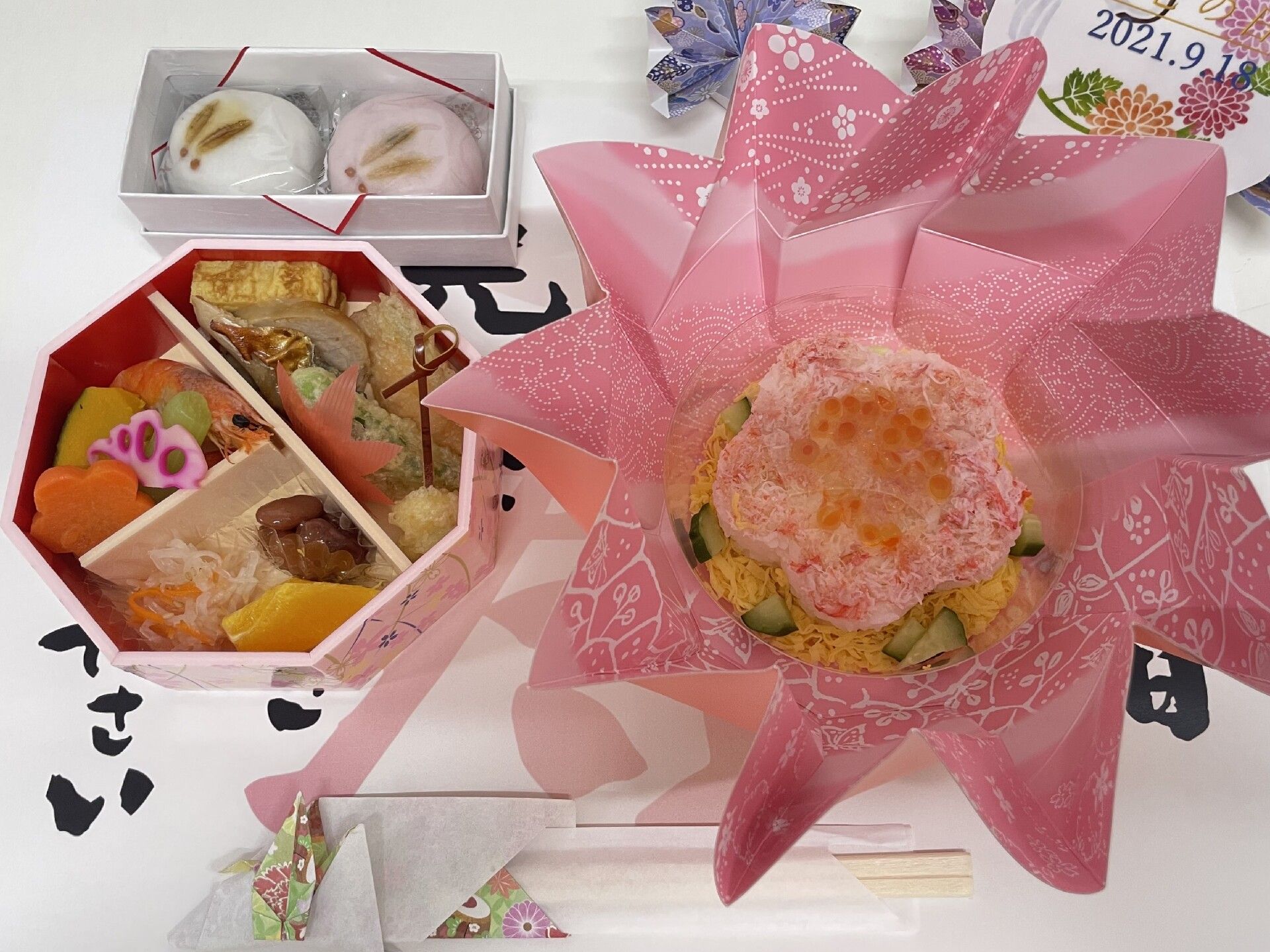 花形の寿司が右側に、左側には煮物やシュウマイなどが詰められた弁当風の箱に入ったおかずがあり、ウサギの饅頭も添えられている。