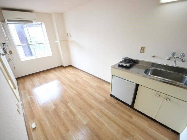 家具が置かれていないフローリングの部屋にはエアコンや大きな窓があり、冷蔵庫付きのキッチンも完備されている。