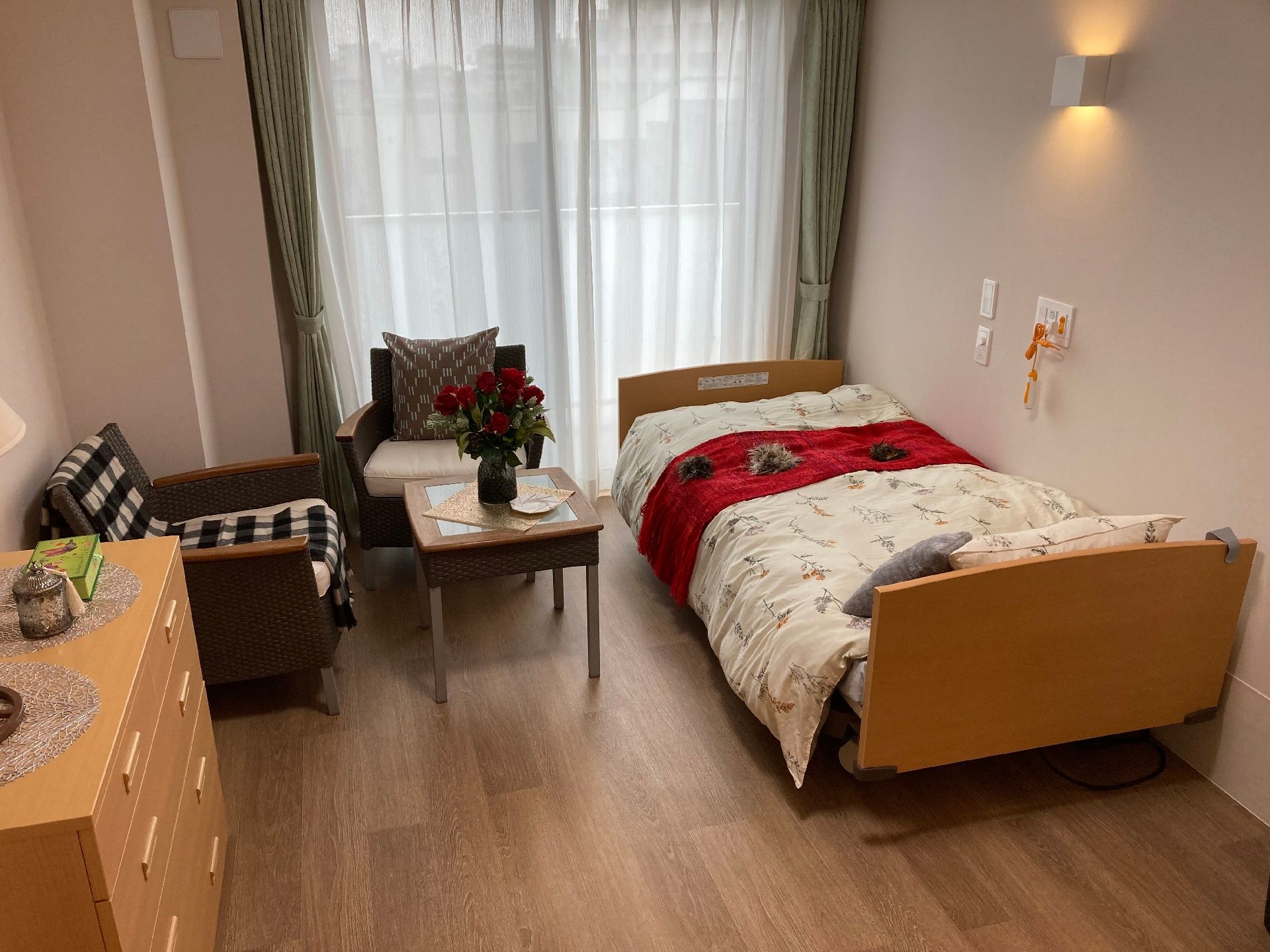オレンジの緊急通報装置が設置された部屋には寝具付きのベッドやタンス、ソファやテーブルが置かれている。