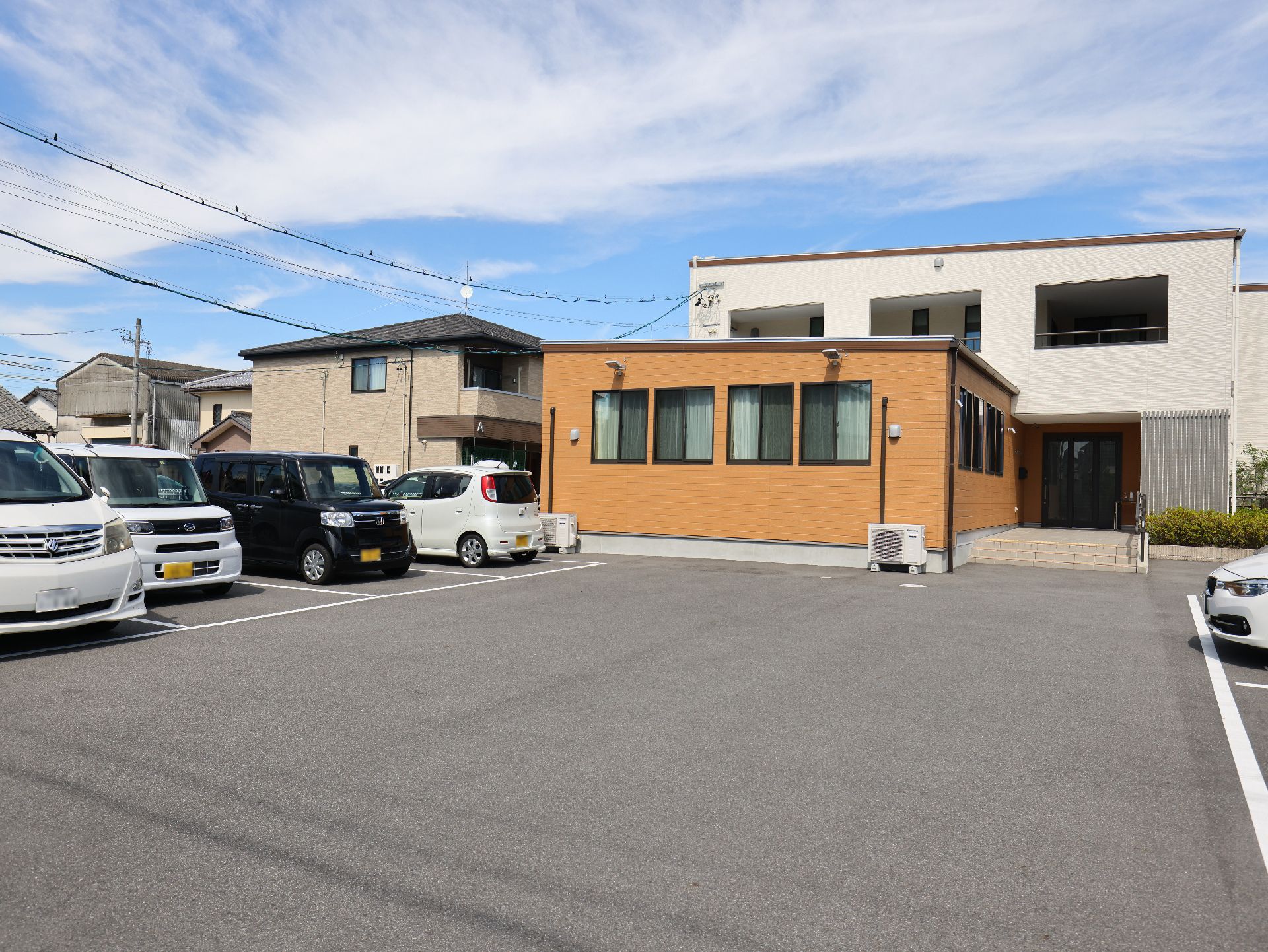 駐車場に隣接したオレンジと白の外観の建物