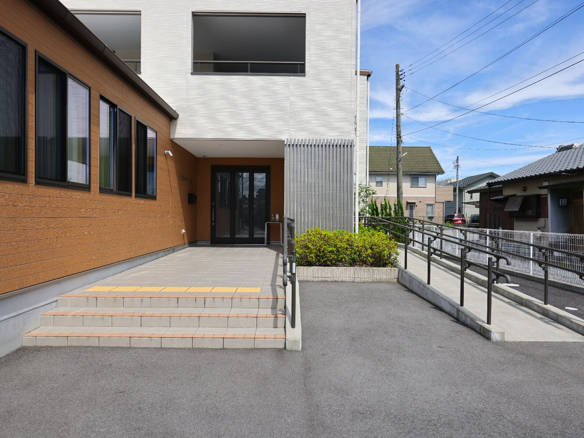 オレンジと白の外観の建物に配置された手すり付きの階段とスロープ