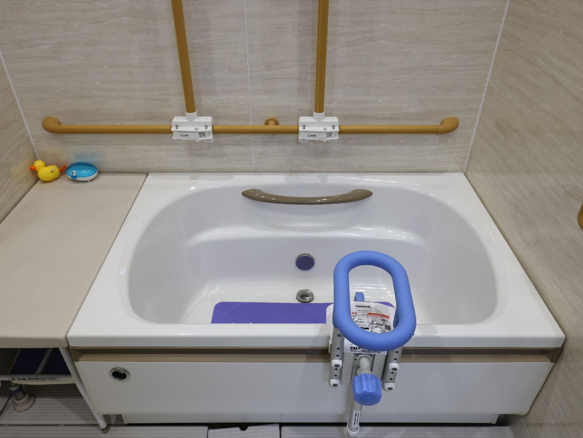 木製の手すりが付いた壁際に配置された白い浴槽