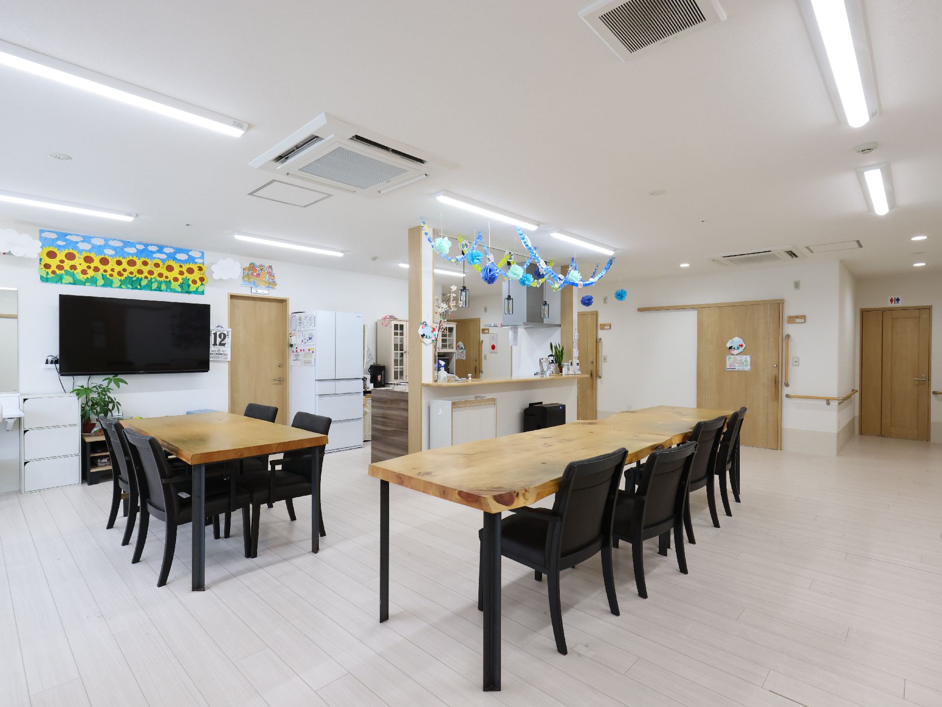 黒い椅子に囲まれた木製の机がある白い壁の部屋