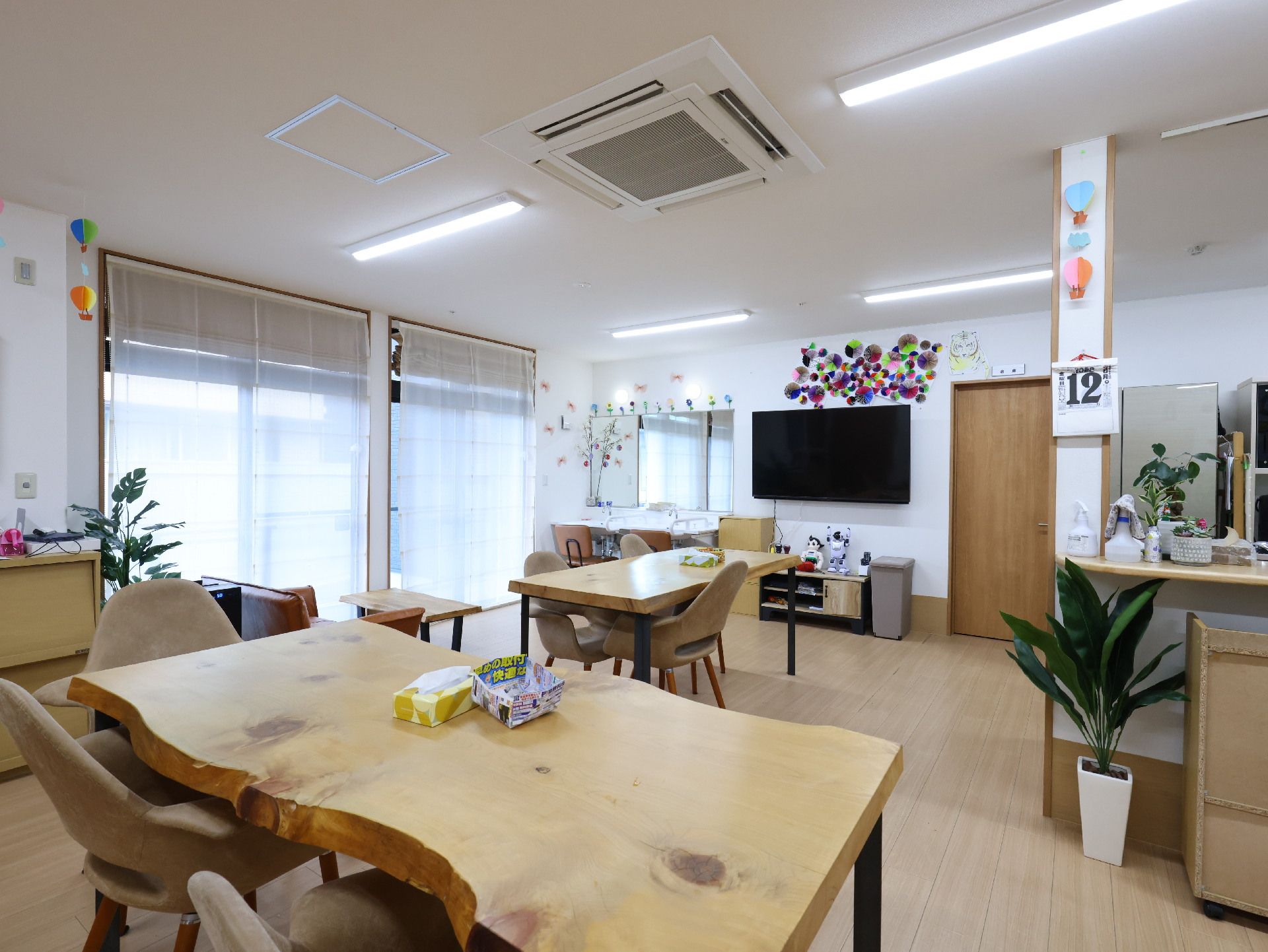木製の机が置かれた白い壁の広間
