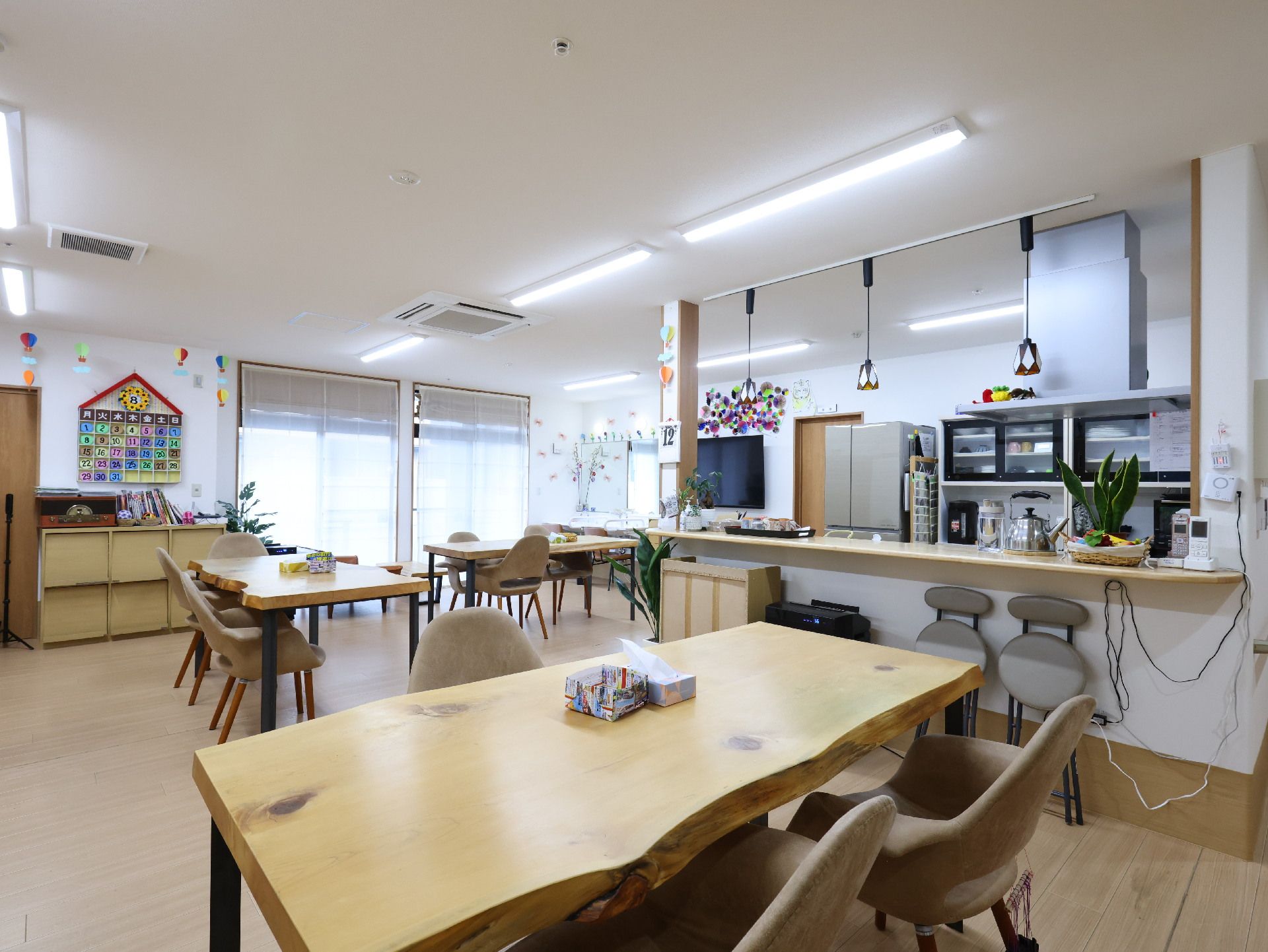 木製の机が置かれた白い壁の広間