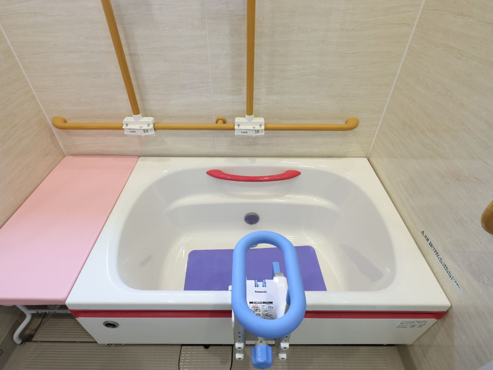 木製の手すりが壁についた部屋の白い浴槽