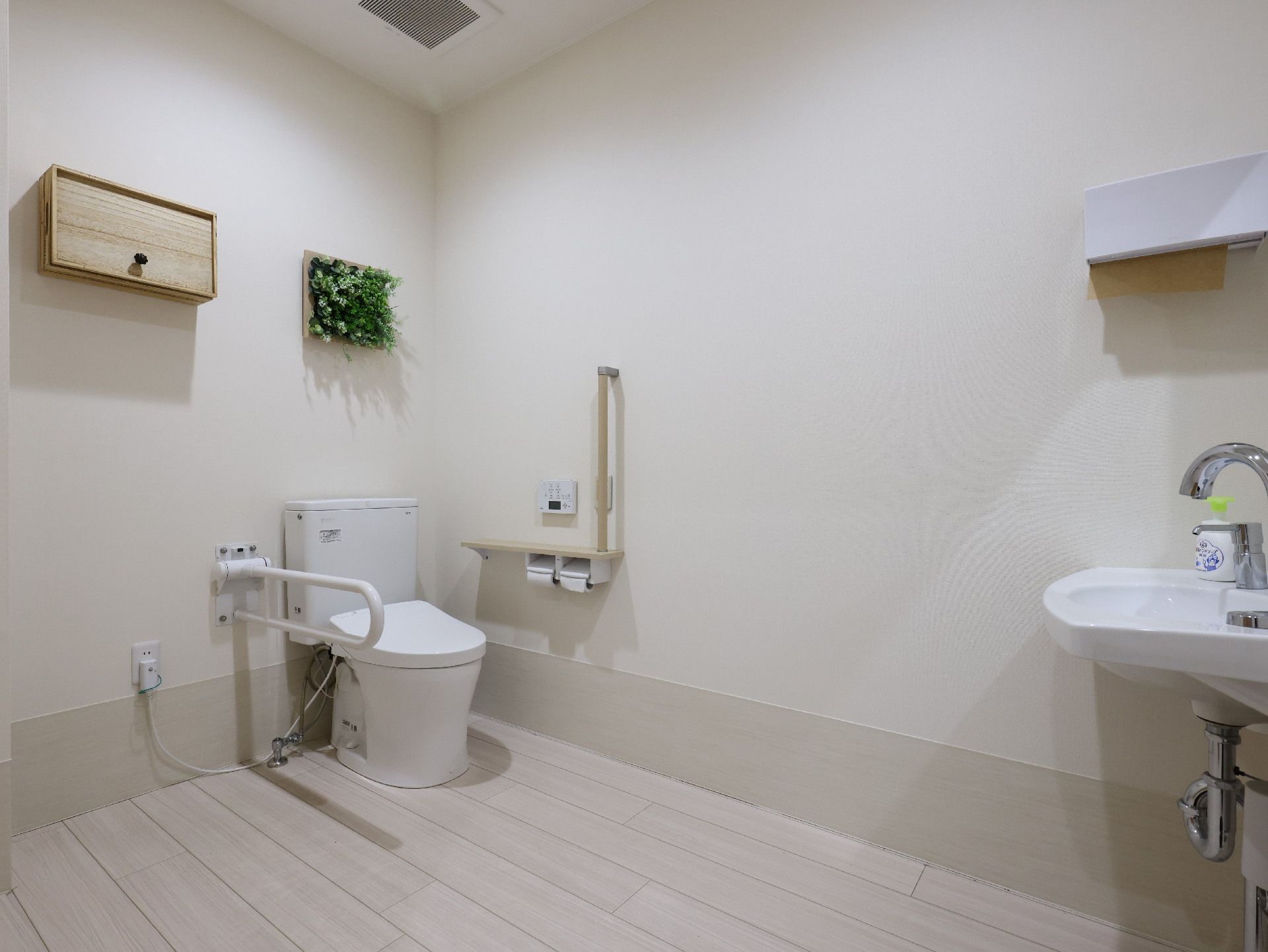 手すりに囲まれた洋式トイレのある白い壁の部屋