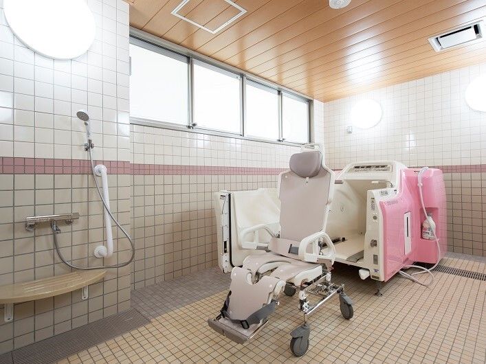 白とピンクの機械浴が設置された浴室はタイル張りで、シャワーが付いている。大きな窓もあり、明るい雰囲気。