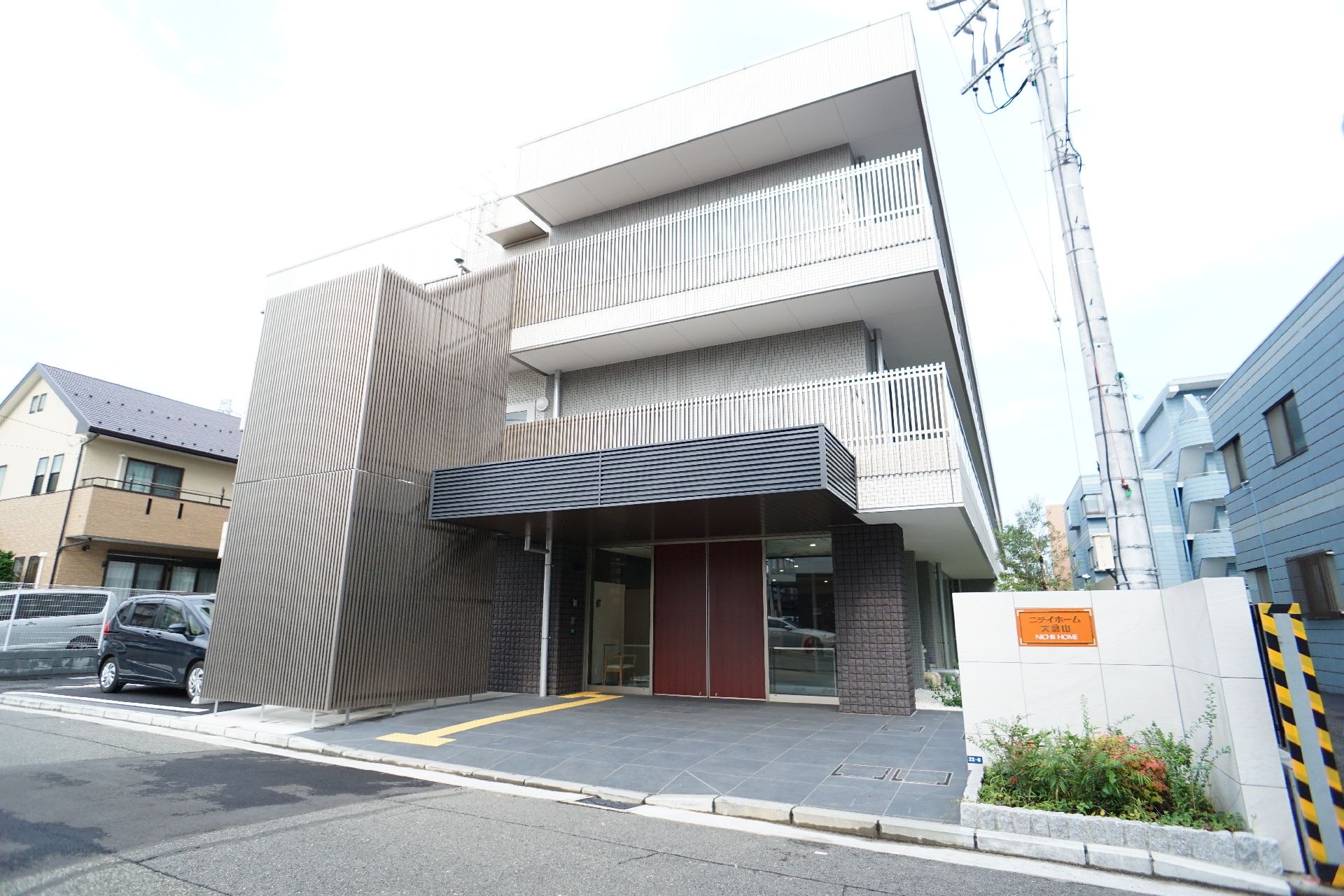 道路沿いに立地している白い外観で３階建てのベランダが付いている建物