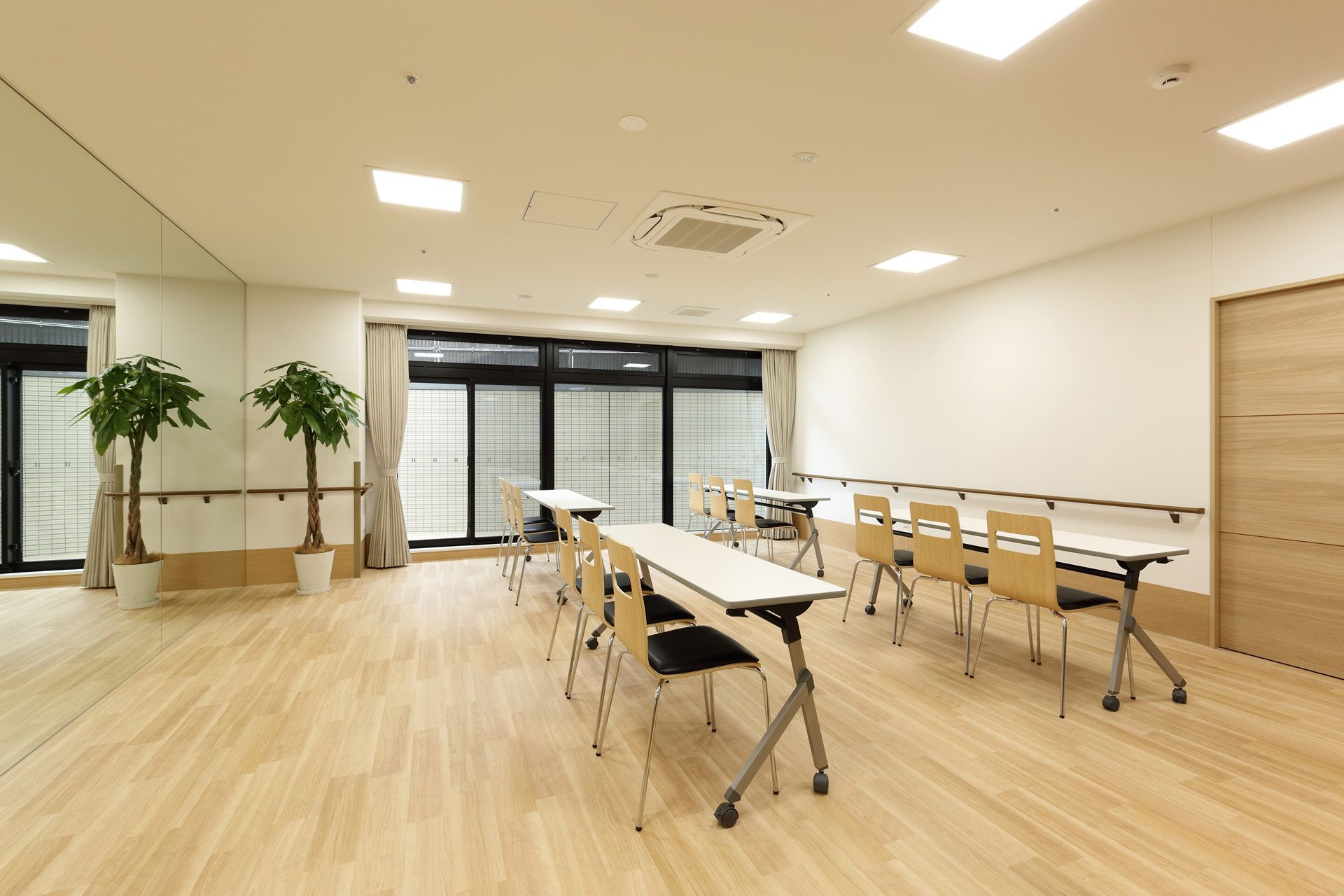 3人掛けの長テーブルが同じ方向を向いて複数設置されてりう。観葉植物が飾られ、手すりも付いている。