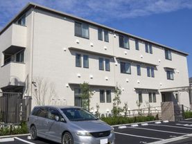 手前に駐車場がある建物の外観パース。入り口付近に雨除けがある様子