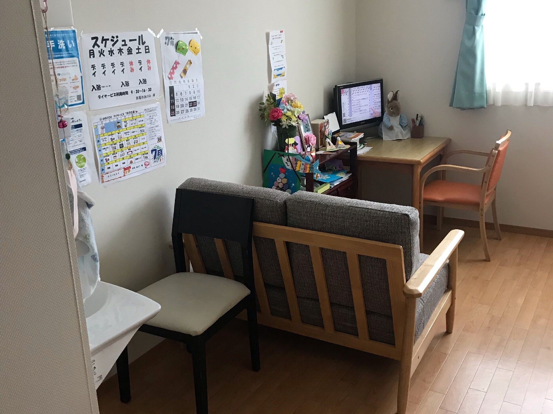 カメラに向かって笑顔を見せるスタッフと高齢者の女性。施設での何気ない一場面の様子