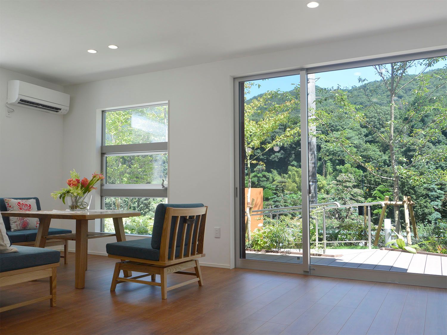 緑あふれる風景を眺めることができる大きな窓が付いたリビングダイニング。ソファやダイイングテーブルが置かれ、日当たりのいい場所。